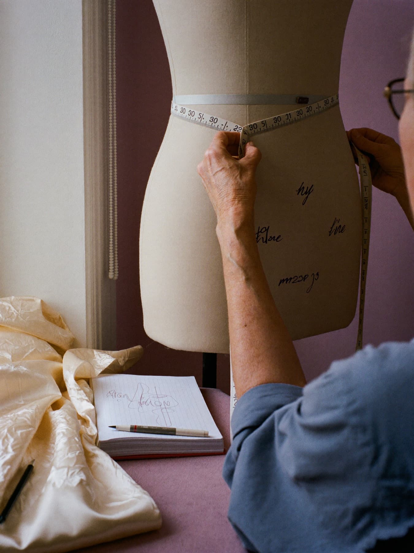 Une couturière mesure la taille d'un mannequin de couture au mètre ruban